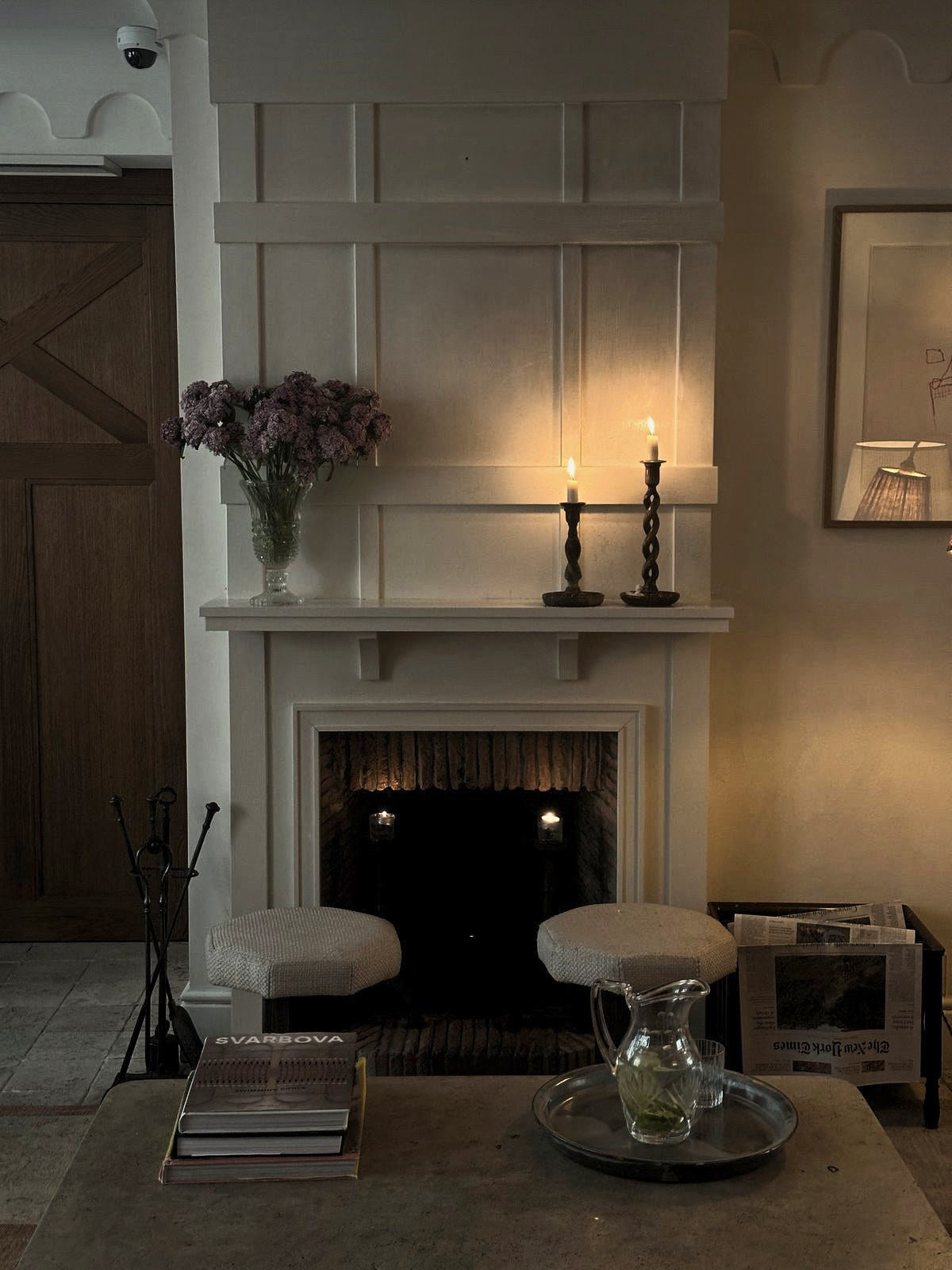 Candles on a white mantel above a lit fireplace