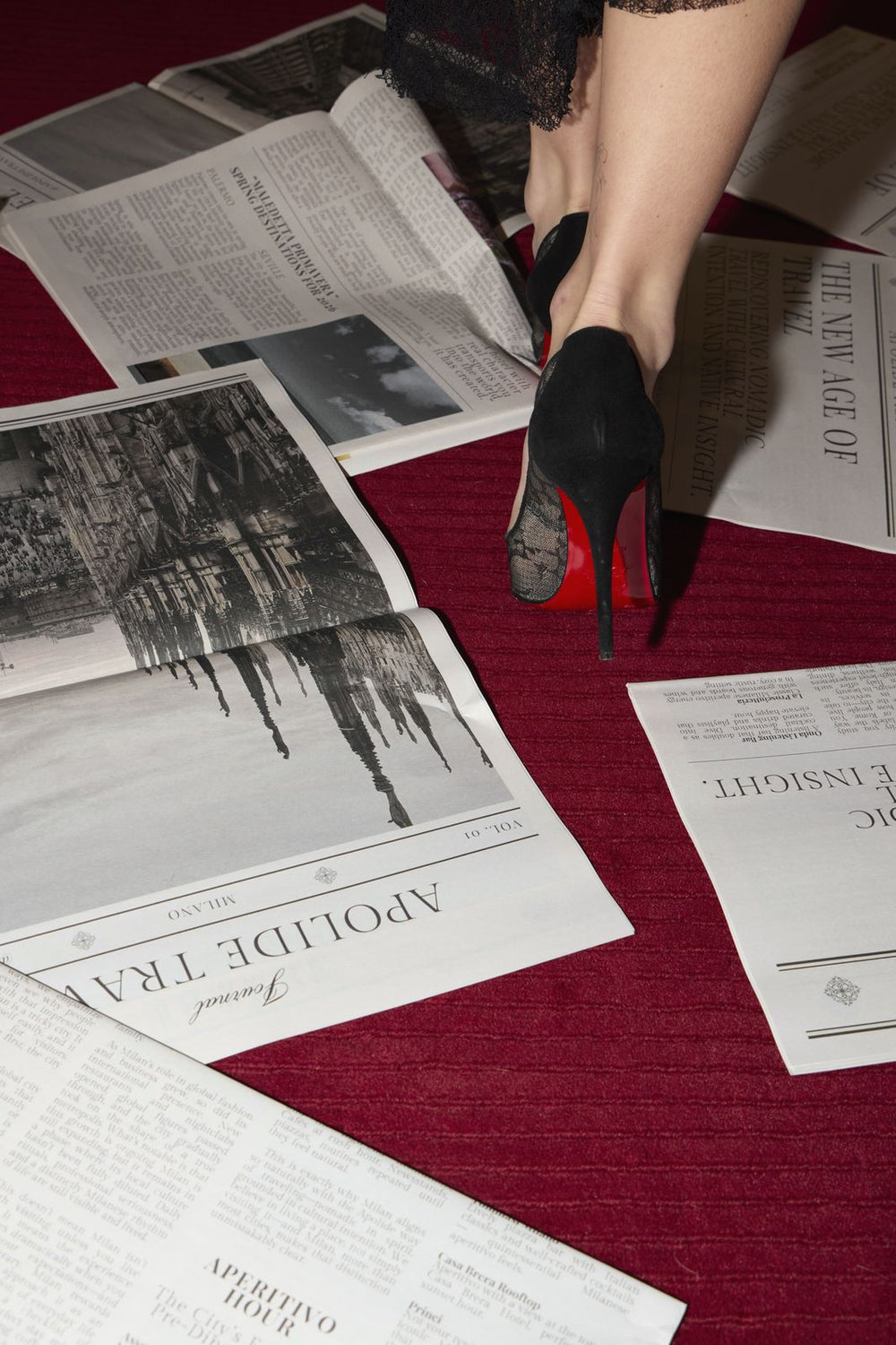 Apolide Journal pages scattered on a red carpet, black heels