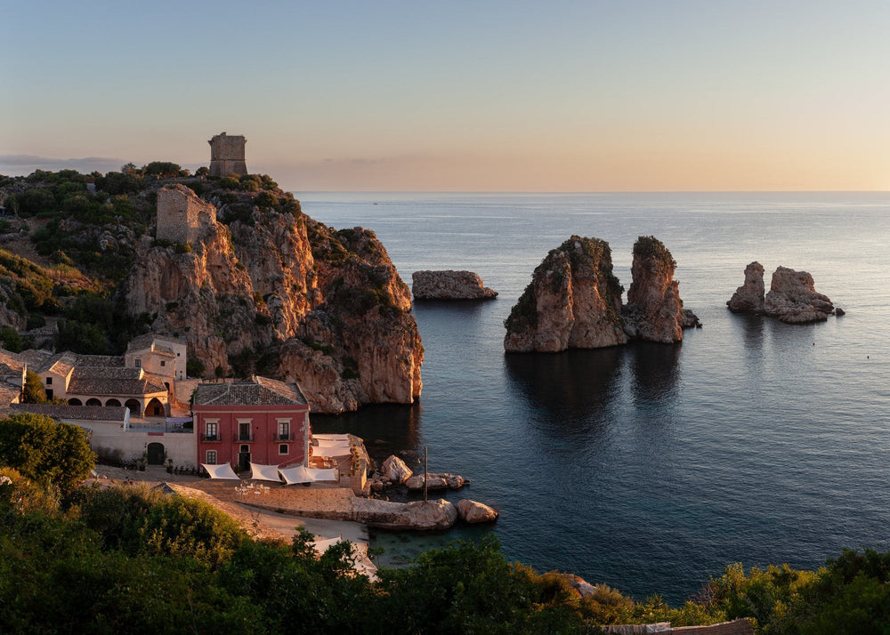 An old tuna fishery and watchtowers above a cove with sea stacks at dusk, Sicily