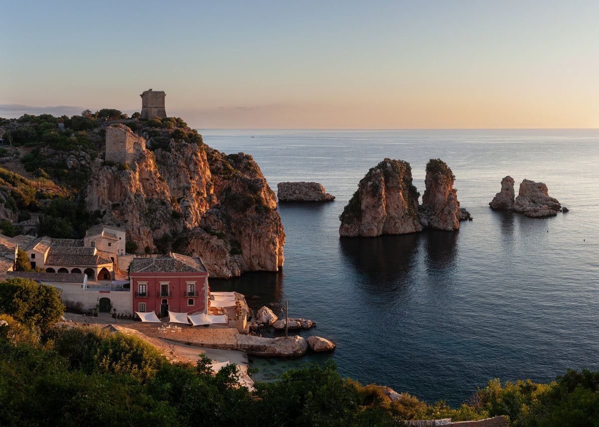 An old tuna fishery and watchtowers above a cove with sea stacks at dusk, Sicily