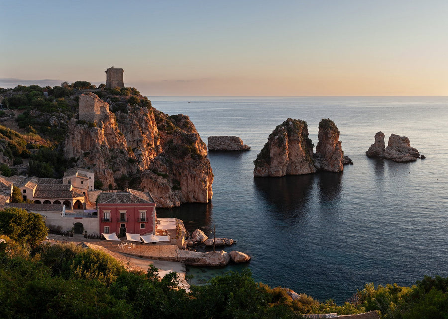 An old tuna fishery and watchtowers above a cove with sea stacks at dusk, Sicily